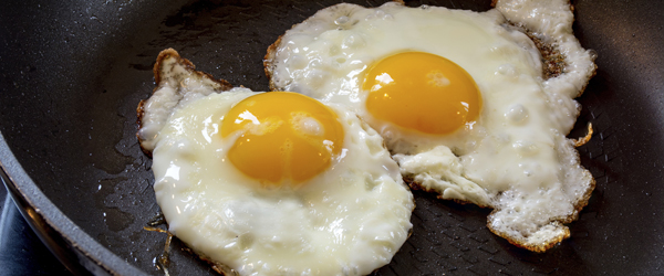 two fried eggs in a black pan